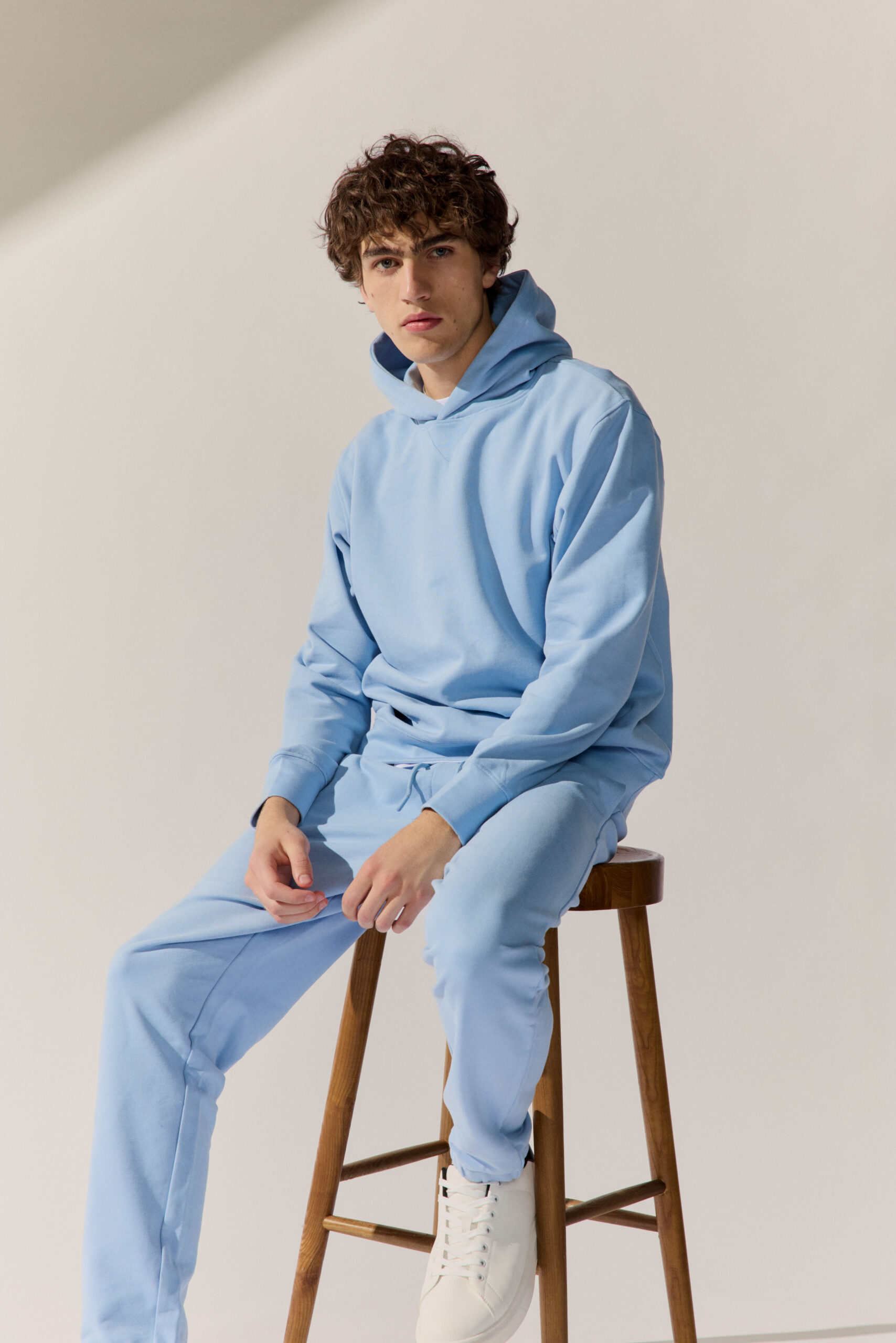 Basefield Men Model sitzt auf einem Stuhl und trägt einen blue dust Troyer