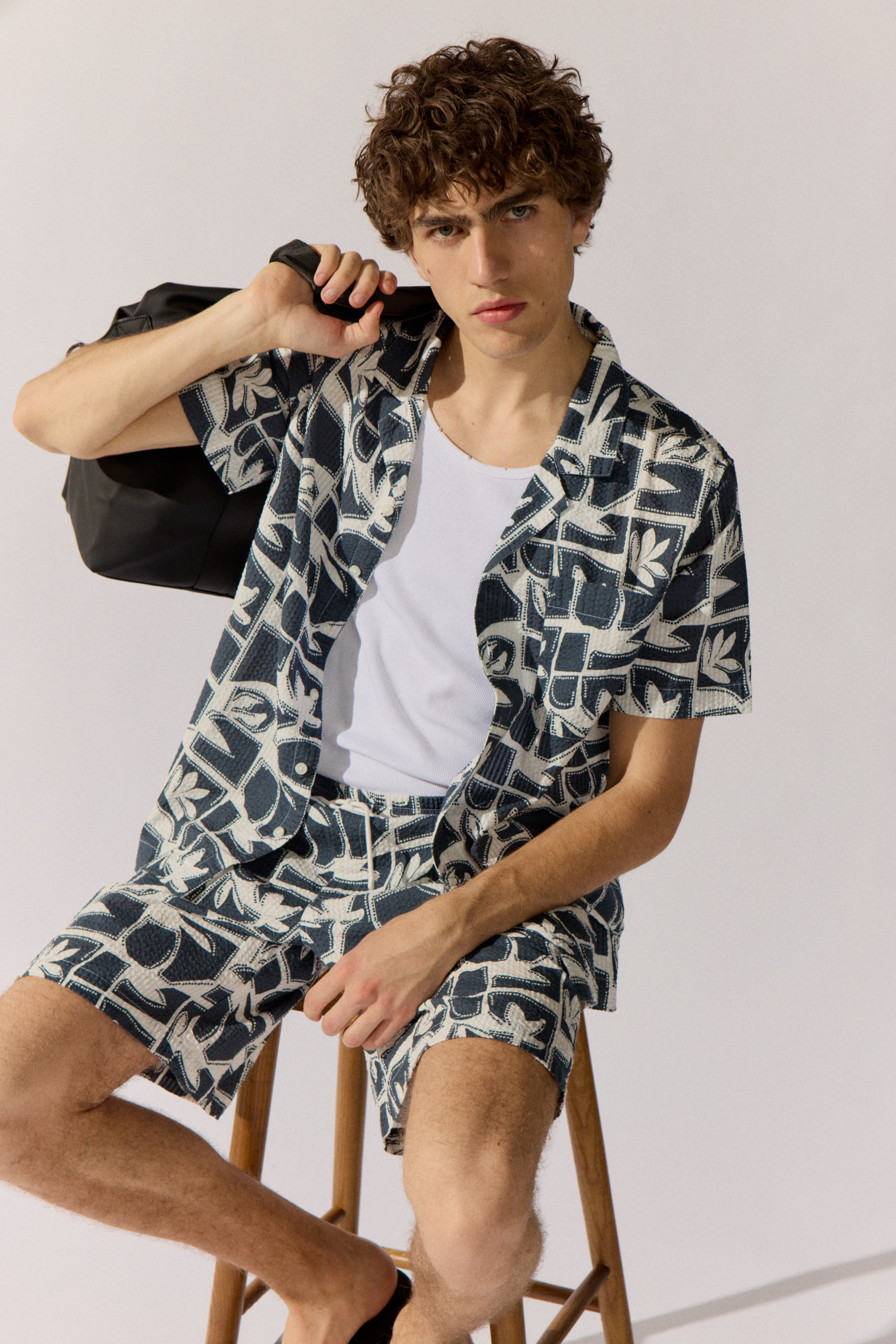 Basefield Men Model trägt mint outift und lehnt sich an einen Stuhl