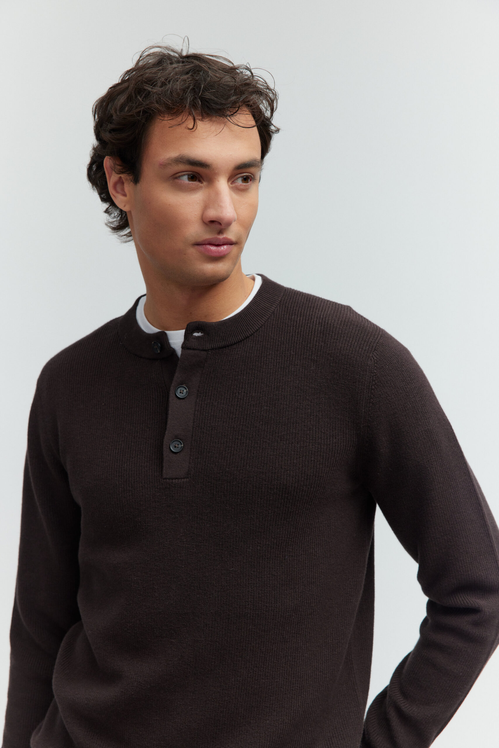 Porträt eines Models im moccabraunem Henley-Pullover mit Knopfleiste.